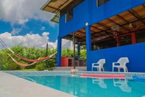 a swimming pool with two chairs and a blue building at Guacamayo Azul in Iquitos
