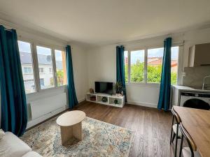 a living room with blue curtains and a table at Pause détente proche du Zénith & Atlantis in Saint-Herblain