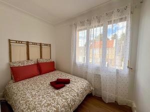 a bedroom with a bed with red pillows and a window at Pause détente proche du Zénith & Atlantis in Saint-Herblain