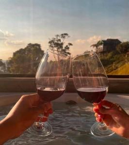 two people holding glasses of red wine at Chalé Bella Vista 03 in Água Boa