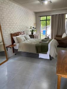 a bedroom with a large bed and a brick wall at The Cozy Acre Unit 2 in Potchefstroom