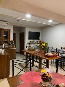 a living room with tables and chairs and a flat screen tv at Hotel Zona Sul in São Gabriel