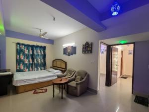 ein Schlafzimmer mit einem Bett, einem Stuhl und einem Tisch in der Unterkunft Cox Flat Booking in Cox's Bazar