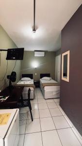 a room with two beds and a table and a desk at Hotel Colonial Bragança Paulista in Bragança Paulista +59 photos