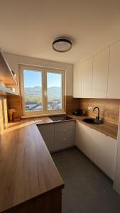 a kitchen with white cabinets and a large window at Apartman Vrućica view in Teslić