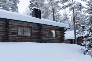 een blokhut met sneeuw op het dak bij Slopeside Luppo - Original Log Cabin, Sauna, Ski 100m in Pyhätunturi +21 foto's