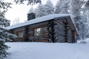 een blokhut met sneeuw op het dak bij Slopeside Luppo - Original Log Cabin, Sauna, Ski 100m in Pyhätunturi