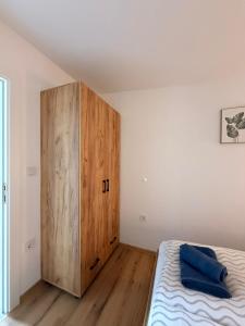 a bedroom with a wooden cabinet next to a bed at Apartman Krznarić Centar in Županja
