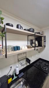 a kitchen with a stove and shelves with pots and pans at Apartamento inteiro in Ponta Grossa