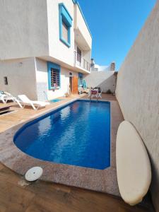 a swimming pool in front of a house at AZULI ⵣ Hostel Mirleft in Mirleft