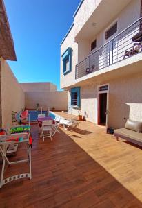 a patio with chairs and a table and a building at AZULI ⵣ Hostel Mirleft in Mirleft