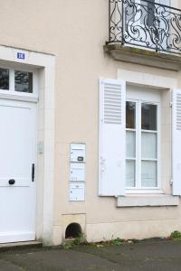 a building with a white door and a window and a door at Le Studio Vert in La Flèche