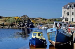 two boats docked in the water next to a building at Teach Hudi Beag, Bar & Accommodation Bunbeg in Bunbeg +11 photos