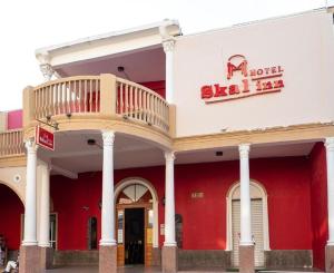 a red and white building with a balcony on it at Hotel Skal Inn in Barranquilla