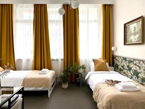 two beds in a hotel room with yellow curtains at Expo Śniadeckich in Poznań