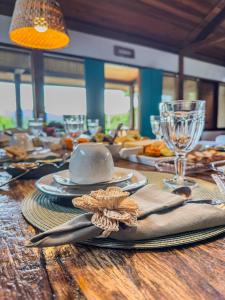 a wooden table with a table set with plates and glasses at Pousada na Cervejaria Altezza - vista para Pedra Azul in Venda Nova do Imigrante