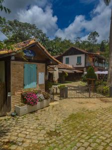 a building with a gate and flowers in a courtyard at Pousada na Cervejaria Altezza - vista para Pedra Azul in Venda Nova do Imigrante +35 photos