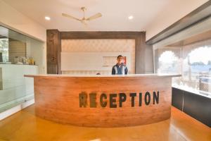 a man standing at a reception counter in a kitchen at Capital O Amit Palace in Bhilwara