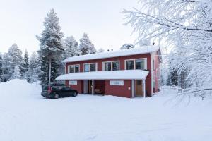a red house with a car parked in the snow at Pyhäkoti A - 30 Meters From the Slopes - Valkea Homes in Pyhätunturi