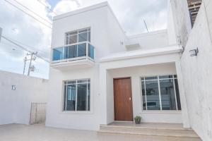 a white house with a brown door at Casa completa con alberca en Chetumal in Chetumal