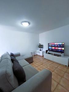 a living room with a couch and a flat screen tv at Casa Pão - 5 mins from Machico centre with private parking in Machico