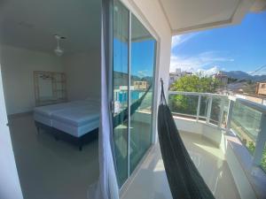 a bedroom with a bed and a hammock on a balcony at Requinte e Conforto na Praia do Morro in Guarapari