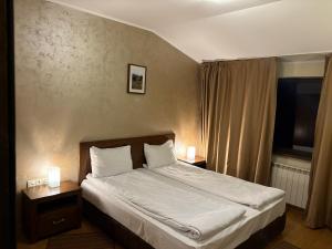 a bedroom with a bed with two nightstands and two lamps at Hotel Smilen in Smolyan