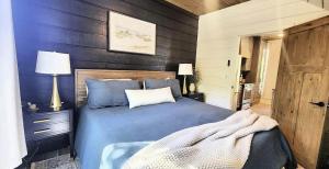 a bedroom with a blue bed with a wooden wall at The Pointe Guesthouse in Texanna