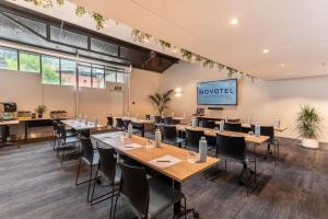a conference room with tables and chairs and a projection screen at Novotel Queenstown Lakeside in Queenstown
