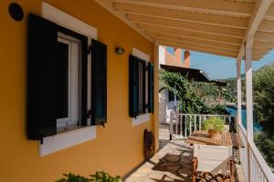 a balcony of a house with black shutters at Yioka House in Mikros Gialos +72 photos
