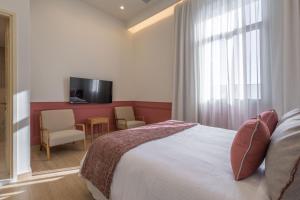 a bedroom with a bed and a tv and a table at Promenade Chios Port Residences in Chios