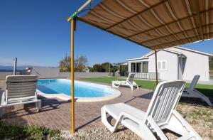 a group of chairs sitting around a swimming pool at Nane Garden house with heated pool in Mirce