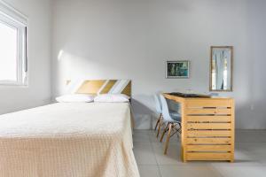 a bedroom with a bed and a dresser and a desk at Pousada Caminho Nômade in Praia do Rosa