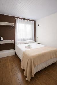 a bedroom with a large white bed with a window at Pousada da Heloisa in Imbituba