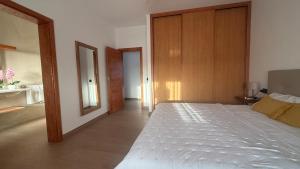 a bedroom with a large white bed and a wooden wall at Yellow Room - Sunlite Double Private Room in Villa Barbuja in Tefía