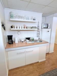 a white kitchen with a sink and a refrigerator at CentRum turistlogi in Borås +29 photos