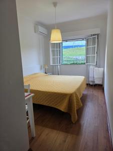 a bedroom with a bed with a yellow bedspread and a window at Gorgeous House in Ponta Delgada