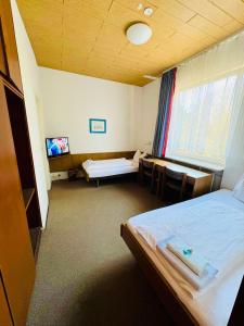 a room with two beds and a table and a tv at Lessinghof in Braunschweig