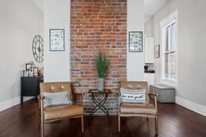 a living room with two chairs and a brick wall at Derby & Bourbon Trail Homebase W Private Backyard in Louisville +95 photos