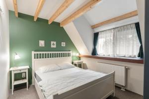 a bedroom with a white bed and a green wall at Riet&Rust in Lanaken