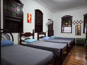 a group of four beds in a room with windows at Vila Mariah Hostel in Belo Horizonte
