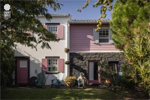 a woman sitting in front of a pink and white house at Quinta da Meia Eira in Horta