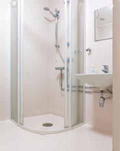 a shower with a glass door next to a sink at Senja Fjord Lodge in Senja