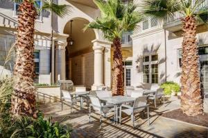 a patio with palm trees and a table and chairs at The Residences At La Cantera in San Antonio