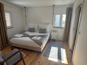a bedroom with a bed and a chair and windows at Retiro Vale do Douro in Vila Marim +33 photos
