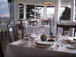 a dining room with a table with white table cloth and glasses at The Colony Hotel Kennebunkport in Kennebunkport