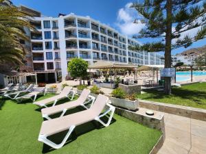 a row of lounge chairs on the lawn in front of a hotel at Ocean Front Cura Beach in Playa del Cura
