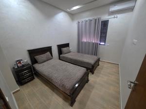 a bedroom with two beds and a night stand at Massira Green Park Serenity in Kenitra