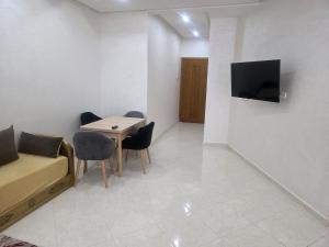 a living room with a table and chairs and a tv at Massira Green Park Serenity in Kenitra