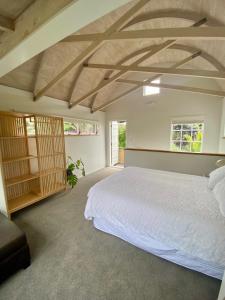 a bedroom with a large white bed in a room at Kauri Coast Bungalow in Karekare